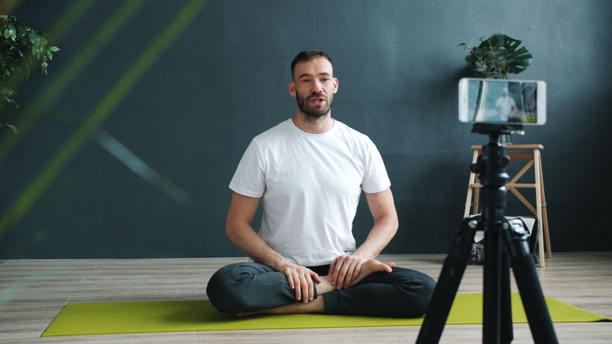 Yoga teacher recording a class with a phone on a tripod