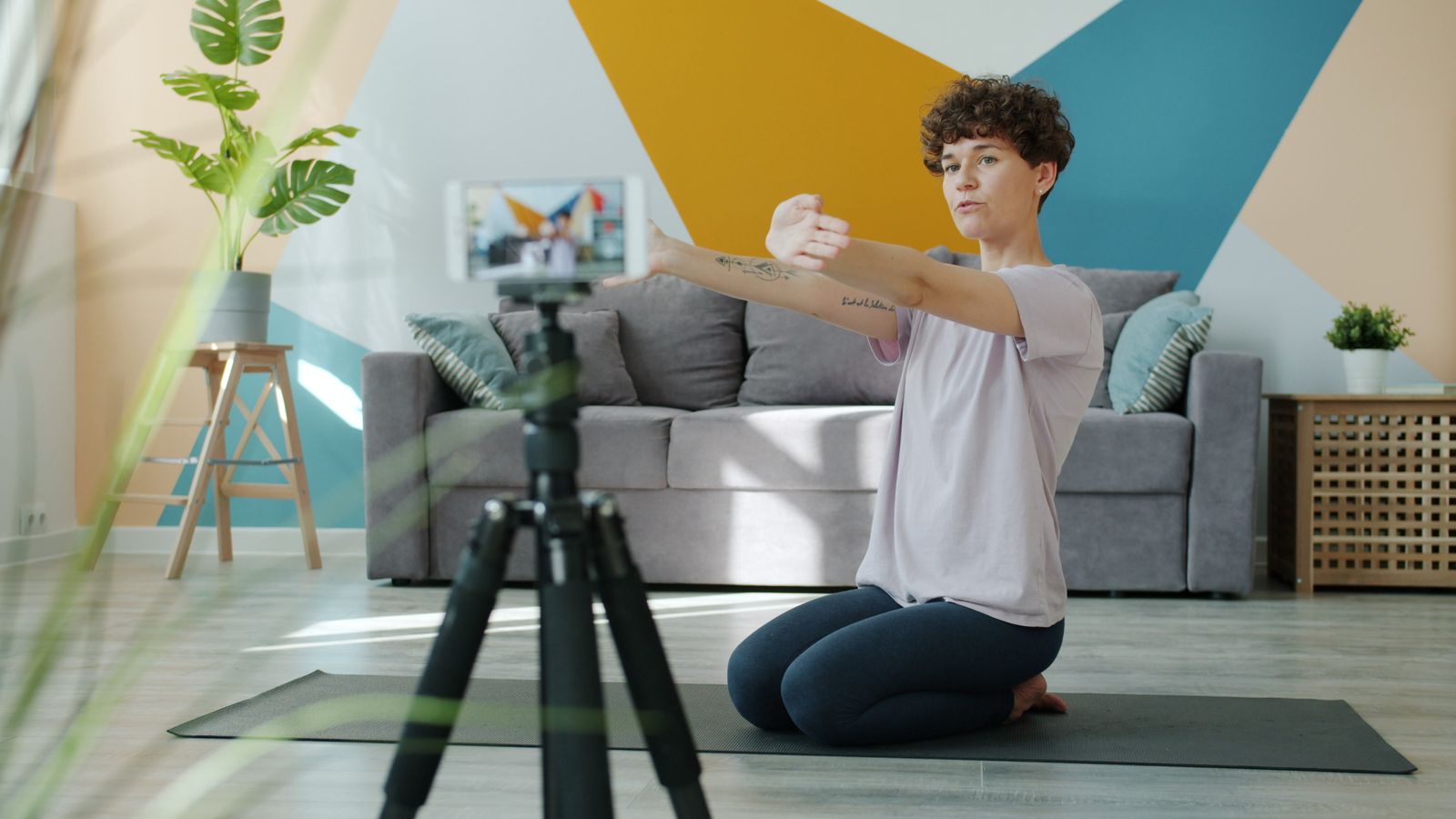 Pilates instructor recording a mat class with a phone on a tripod