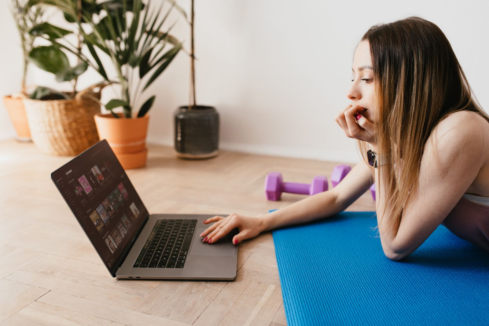 Yoga teacher lying on a mat at home checking numbers on a laptop